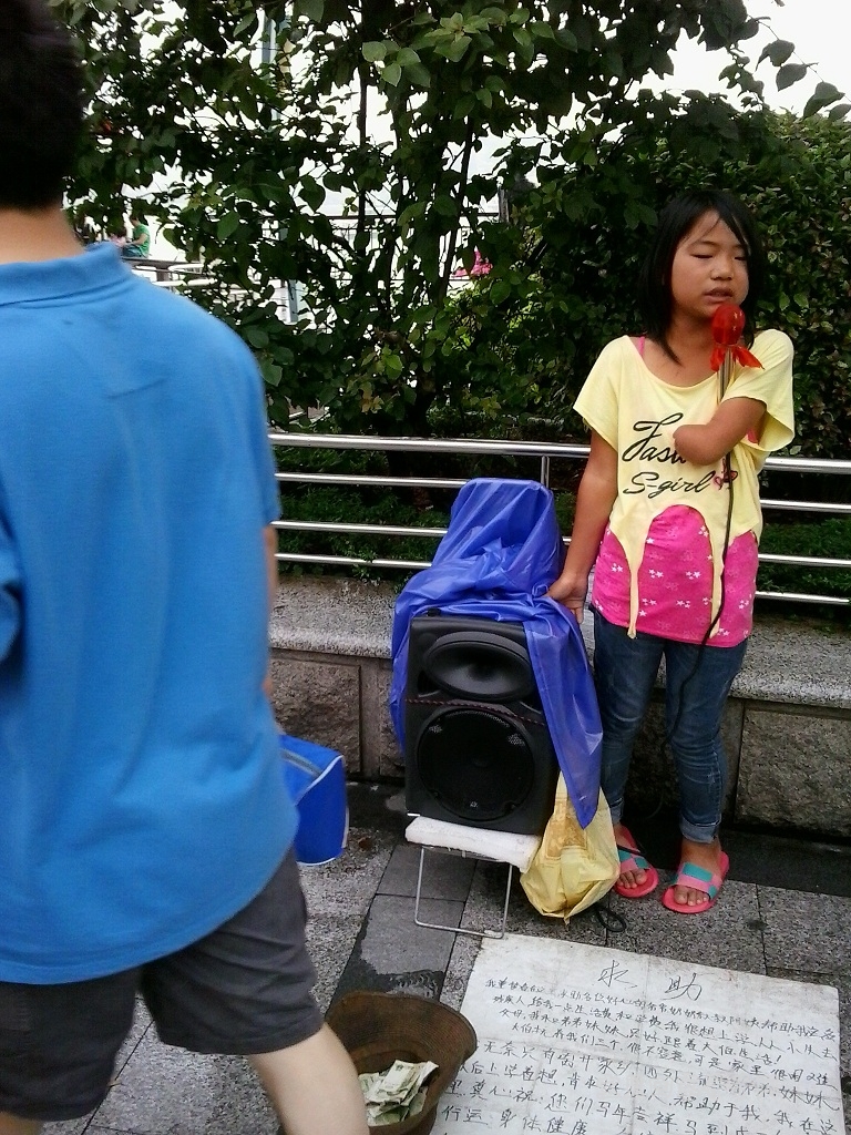 在厦门的繁华街区，小女孩整天唱同一首歌乞讨。
