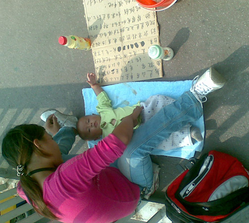在北京市海淀区魏公村车站的天桥上看见一抱小孩乞讨妇女